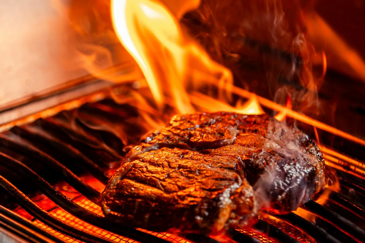 Steak over strong flames as an example of high-heat grilling